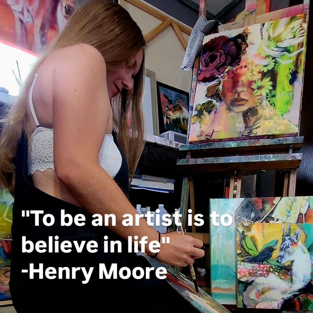 Artist Mandi Murphy is kneeling on the ground working on a painting